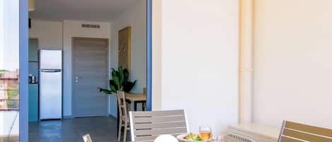 Un coin repas avec une table dressée pour deux personnes, comprenant des assiettes de nourriture, des verres de vin et du pain.