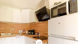 A modern kitchen with white cabinets, a wooden countertop, a built-in microwave, and a refrigerator.