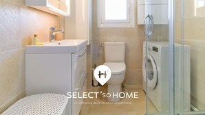 A modern bathroom with a toilet, sink, and glass shower enclosure.