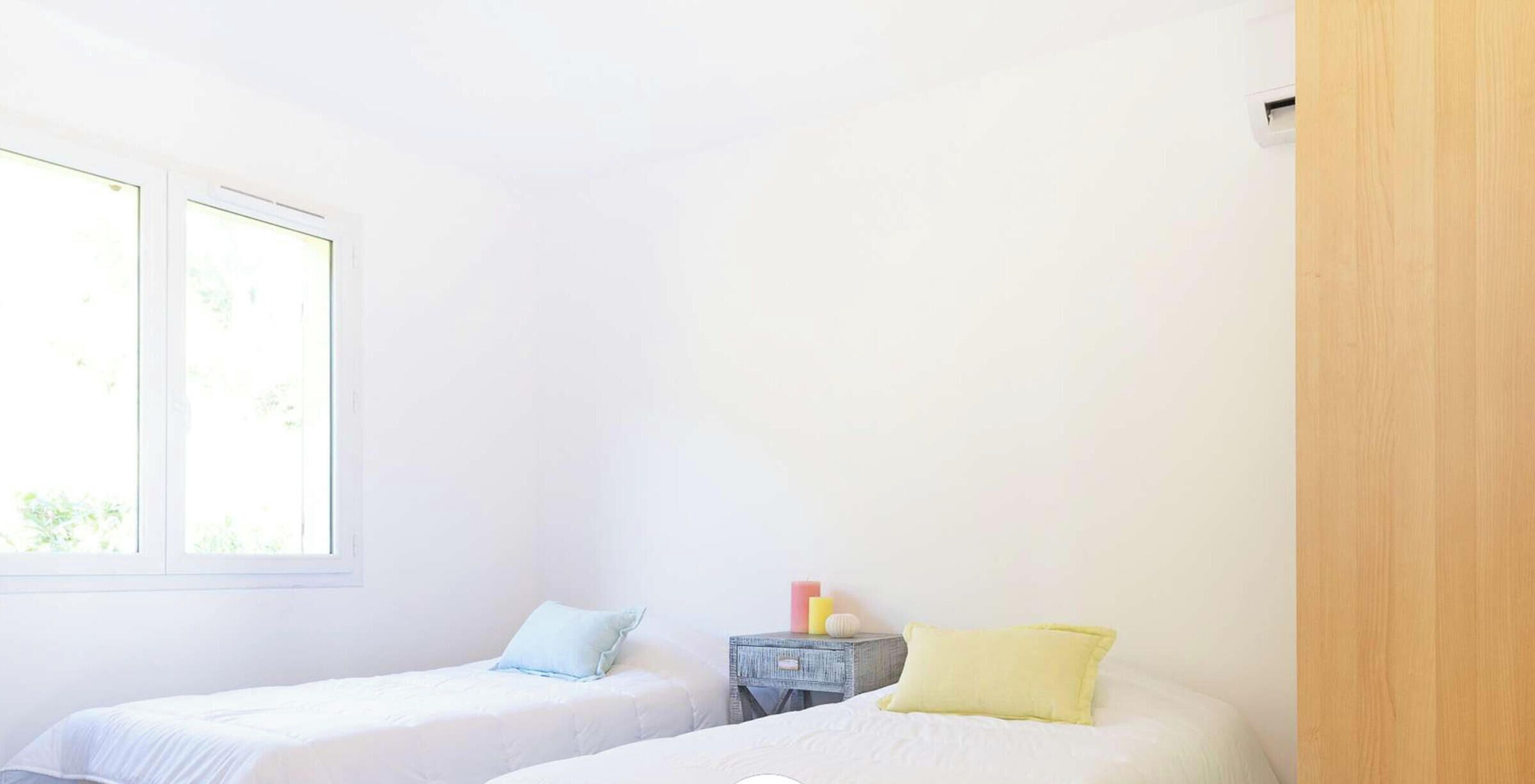 A room with two beds, a small table with candles, and a window.