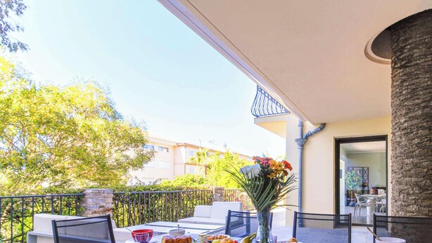 An outdoor patio with a stone pillar, a white sofa, and a dining table with chairs. - Stunning Villa 8 pers - Jacuzzi - Large Spaces (Le Lavandou)