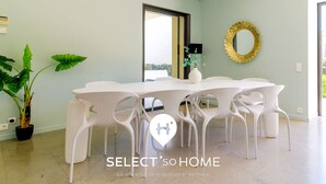 A modern dining area with a white table and chairs, a potted plant, and a decorative mirror on the wall. - Stunning Villa 8 pers - Jacuzzi - Large Spaces (Le Lavandou)