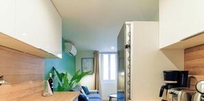 A compact living space with a kitchenette, a dining area, and a window providing natural light.