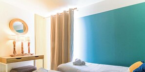 A hotel room with a bed, a desk with a mirror, and a window with curtains.