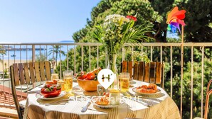 A round table set outdoors with a view of the sea, a flower vase, and a pinwheel. - Duplex in Lavandou, Pets Allowed, Parking (Le Lavandou)