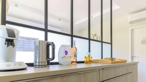 A kitchen counter with a coffee maker, a kettle, a bag, a bottle, and a tray.