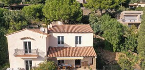 A two-story house with a tiled roof, a balcony, and a covered patio area. - Quiet Family Villa with Private Pool (Le Lavandou)