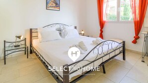 Une chambre à coucher avec un lit, deux tables de chevet, une commode, une fenêtre avec des rideaux rouges et un tableau accroché au mur.