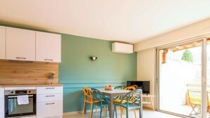 Eine moderne Küche mit weißen Schränken, einer Holz Arbeitsplatte und einem eingebauten Backofen. Ein Essbereich mit Tisch und bunten Stühlen ist ebenfalls vorhanden.