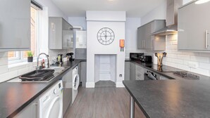 Een moderne keuken met een ingebouwde wasmachine, een klok aan de muur en een magnetron.