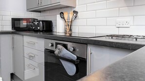 Een moderne keuken met een magnetron, oven en gasfornuis.