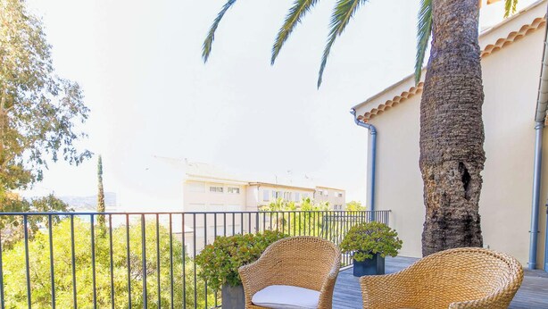 A balcony with wicker chairs, a potted plant, and a palm tree. - Bright loft in Le Lavandou center, pets allowed, 2 bedrooms (Le Lavandou)