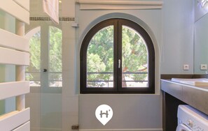A modern bathroom with a large arched window, a washing machine, and a towel rack. - Bright loft in Le Lavandou center, pets allowed, 2 bedrooms (Le Lavandou)