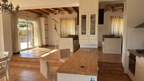 A spacious kitchen with wooden flooring, a central island, and a dining area with a chair.