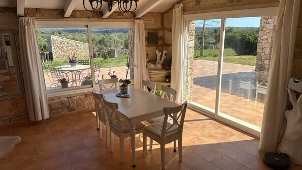 A dining area with a table and chairs, a stone wall, and a view of the outdoors. - Villa Can Susacasa relax with sun swimming pool air conditioning and unobstructed views  (Santa Margalida)