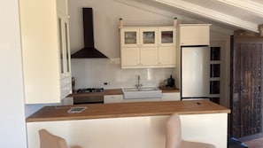 Una cocina con armarios blancos, extractor de aire negro, pileta doble y encimera de madera.