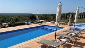 A swimming pool with tiled edges, lounge chairs, and umbrellas. - Villa Can Susacasa relax with sun swimming pool air conditioning and unobstructed views  (Santa Margalida)