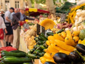 A market stall with various vegetables like zucchini and squash, and a yellow basket. - Studio facing the beach - Parking included (Le Lavandou)