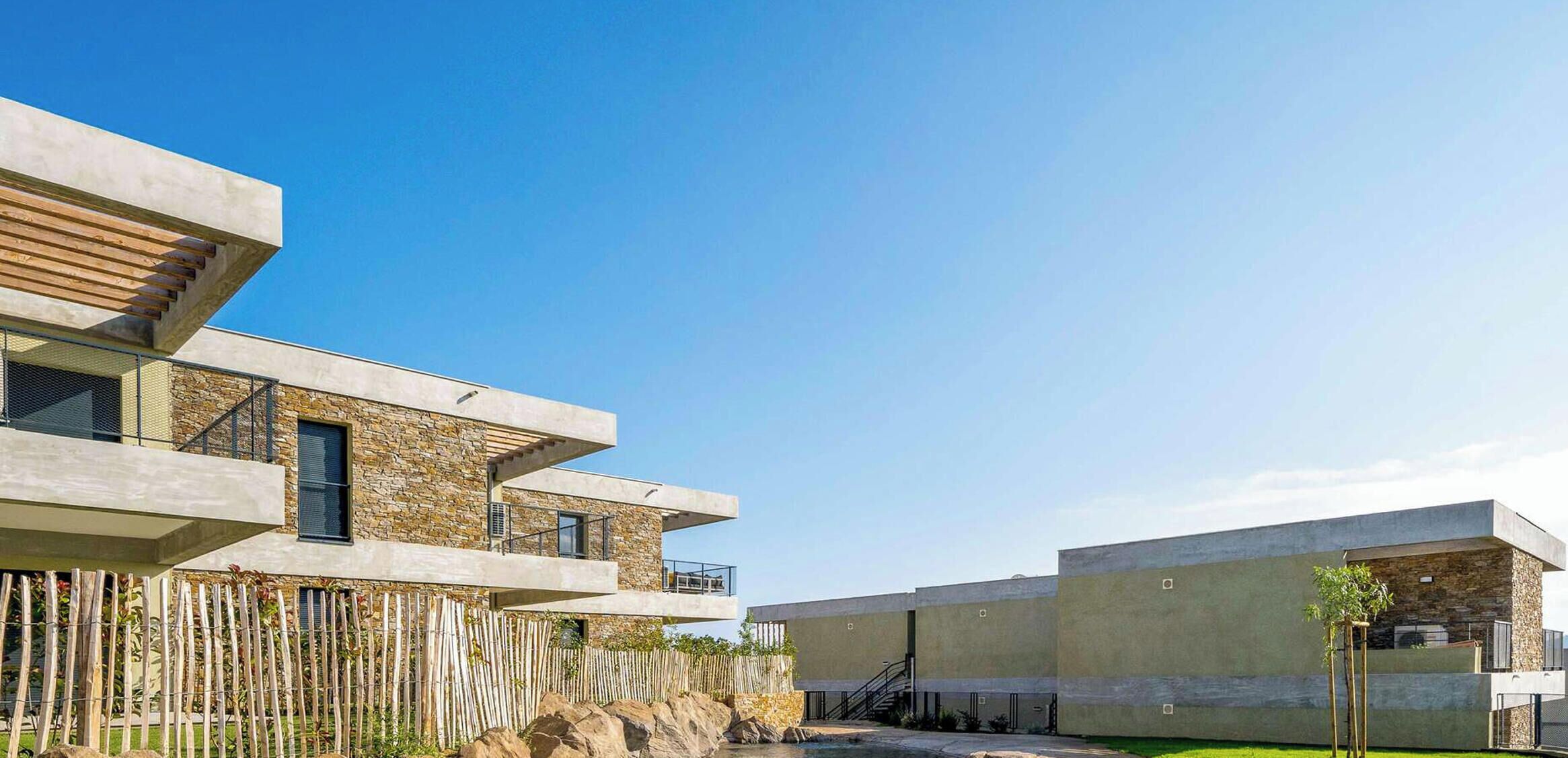 A modern building with multiple levels, balconies, and a stone facade.