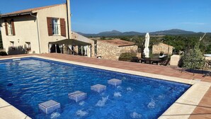 A swimming pool with a view of mountains, a stone wall, and outdoor furniture. - Charming 2-bedroom villa in Santa Margalida with AC, WiFi, fitness room (Santa Margalida)