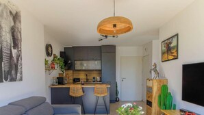 A modern kitchen with dark cabinets, a wooden island, and two bar stools. - Bright apartment with terraces, pool in secure domain (Bormes-les-Mimosas)