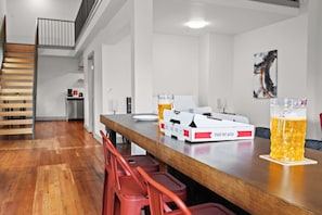 A modern kitchen with a wooden staircase, a bar area with stools, and pizza boxes. - Chic & comfy unit in Louisville's Medical District (Louisville)