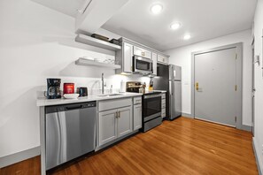 A modern kitchen with stainless steel appliances, white cabinetry, and wooden flooring. - Chic & comfy unit in Louisville's Medical District (Louisville)