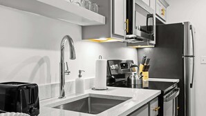 A modern kitchen with a stainless steel refrigerator, a built-in oven, and a microwave. There is a sink with a faucet, a toaster, and a soap dispenser. - Chic & comfy unit in Louisville's Medical District (Louisville)