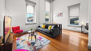 A spacious living room with a grey sofa, red armchair, and a colorful rug. - Chic & comfy unit in Louisville's Medical District (Louisville)