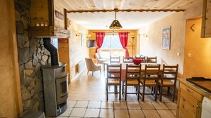 A cozy cabin interior with a stone fireplace, wooden dining table, and chairs.