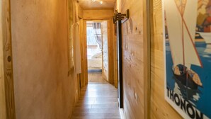 A narrow wooden hallway with a wooden floor, a ceiling fan, and a poster on the right wall.