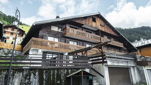 A multi-story wooden building with balconies, a staircase, and a garage.