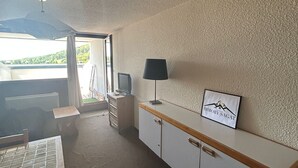 Ein Zimmer mit einer Küchenzeile, einem Schreibtisch, einem Fernseher und einem gerahmten Schild an der Wand.