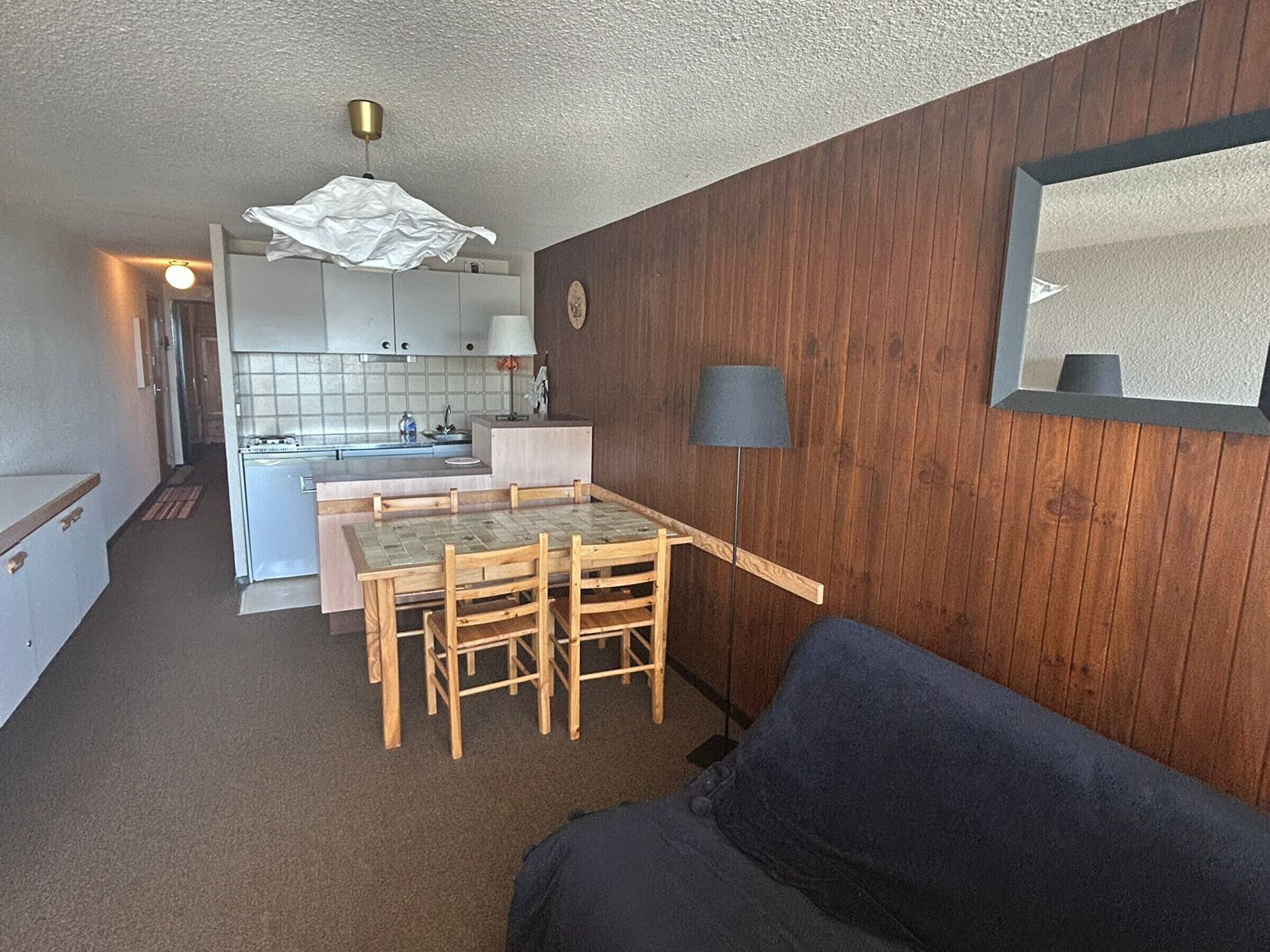 Une cuisine compacte avec un coin repas, un mur en bois et un miroir.