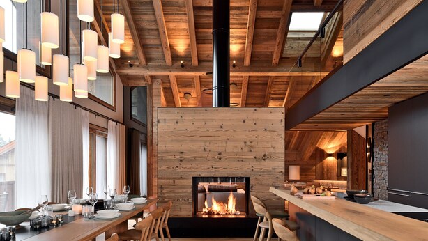 A modern interior with a wooden ceiling, a fireplace, and a dining area with chairs and tables.