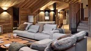 A cozy loft-style living room with a high ceiling, wooden beams, and a modern sofa set.
