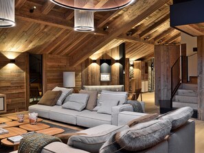 A cozy loft-style living room with a high ceiling, wooden beams, and a modern sofa set.