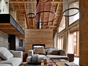 A modern interior with a wooden ceiling, a sofa set, a coffee table, and a hanging light fixture.