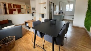 En moderne stue med spiseplads, køkken og en grøn væg.