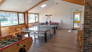 A room with a ping pong table, foosball table, and seating area with wooden chairs. - Chalet in Normandy Near Veules-les-roses (Veules-les-Roses)
