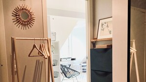 Una habitación con un perchero de madera, un armario negro, un espejo y una puerta que da a un balcón.