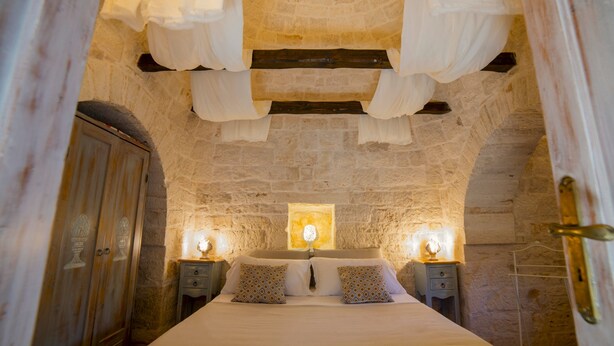 A stone-walled bedroom with a bed, two bedside tables with lamps, and a wooden wardrobe. - Like Once Upon a Time - The Trullo (with Jacuzzi for exclusive use) 2 km from Alberobello (Martina Franca)