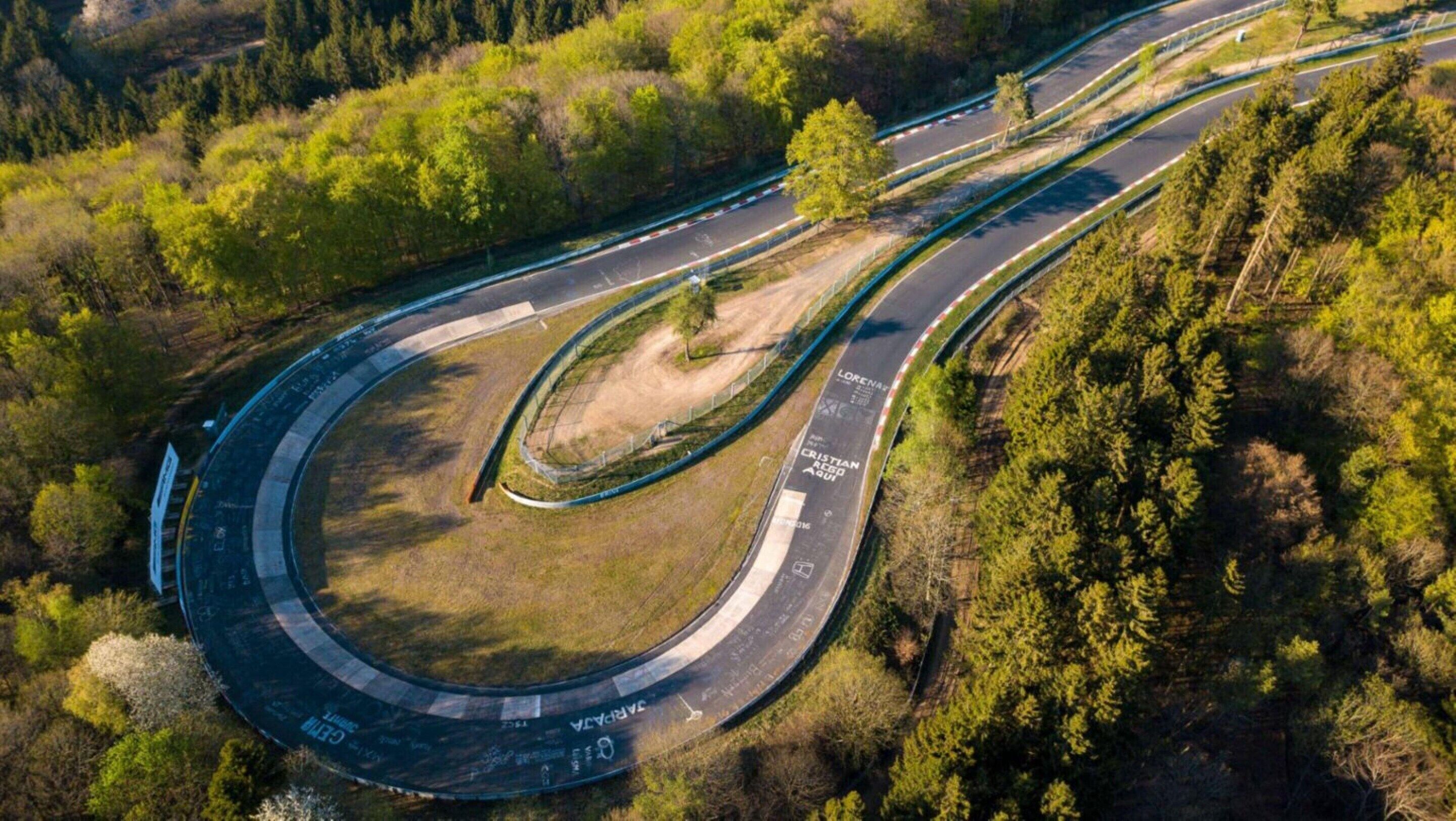 Luchtbeeld van een kronkelende weg met meerdere rijstroken en een middenberm, omringd door dicht bos.