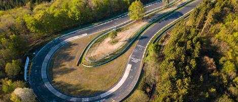 Luchtbeeld van een kronkelende weg met meerdere rijstroken en een middenberm, omringd door dicht bos.