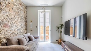 Una sala de estar con pared de piedra, un sofá, un televisor y un mueble de madera.