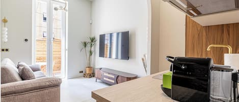 Una cocina moderna con cafetera integrada, un armario de madera y un ventanal amplio.