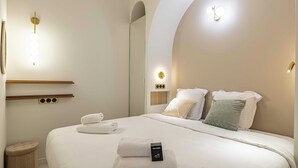 Una habitación de hotel moderna con una cama bien hecha, una mesita de noche con lámpara y un aplique de pared.