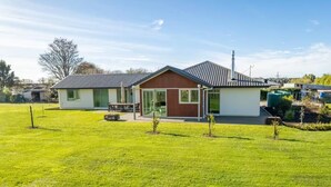 A modern single-story building with a flat roof, a glass door entrance, and a small patio area. - Relax in Riwaka, Sun, Space, Cycle (Riwaka)