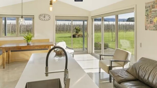 A modern kitchen with a large island, a built-in sink, and a dining area with a bench. - Relax in Riwaka, Sun, Space, Cycle (Riwaka)