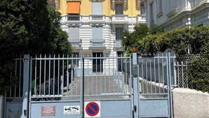 A gated entrance to a yellow building with balconies and a no parking sign.
